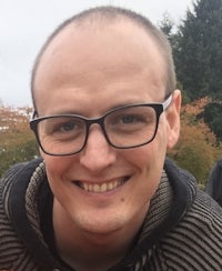 a man in glasses smiles for the camera